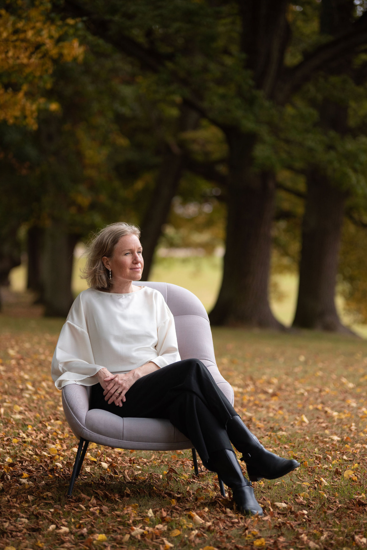 Hanna Billström sitter i en fåtölj bland höstlöv i en allé